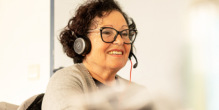 ältere Frau mit Headset am Rechner